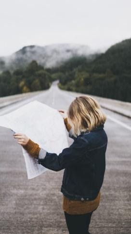 Woman reading a map on a road.